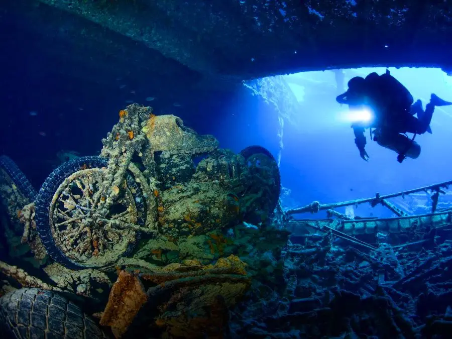 A diver beside encrusted motorcycles inside a shipwreck, shown as a file photo.