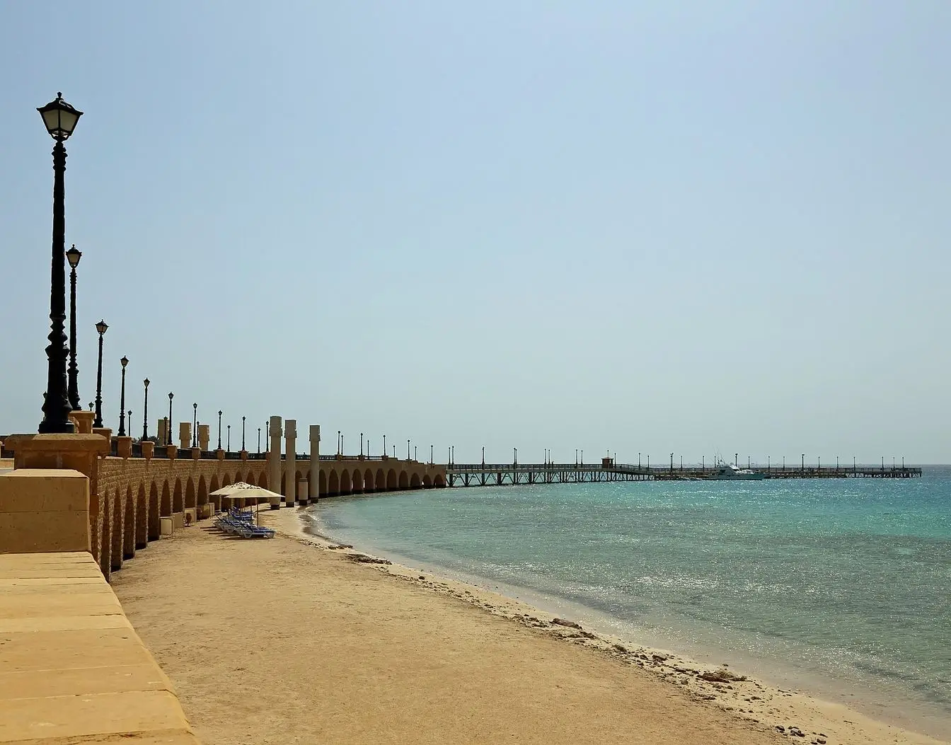File photo of the Sahl Hasheesh seafront: a stone promenade with lampposts beside the beach, a long jetty reaching into the turquoise bay. Representative view of the area, not the planned Capri project.