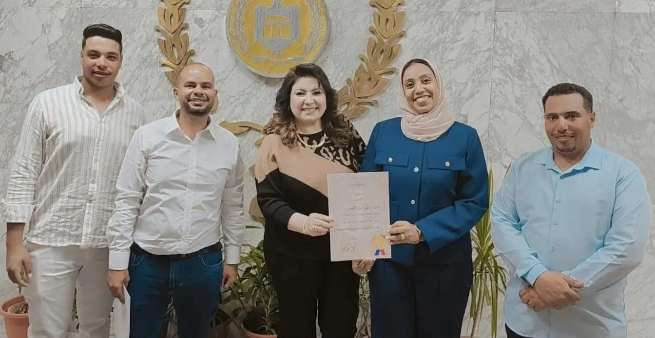 Five people stand together holding an Arabic certificate in front of the Egyptian state emblem. The publisher ran this photograph with its report on the green projects award; the people in it are not named in our reporting.