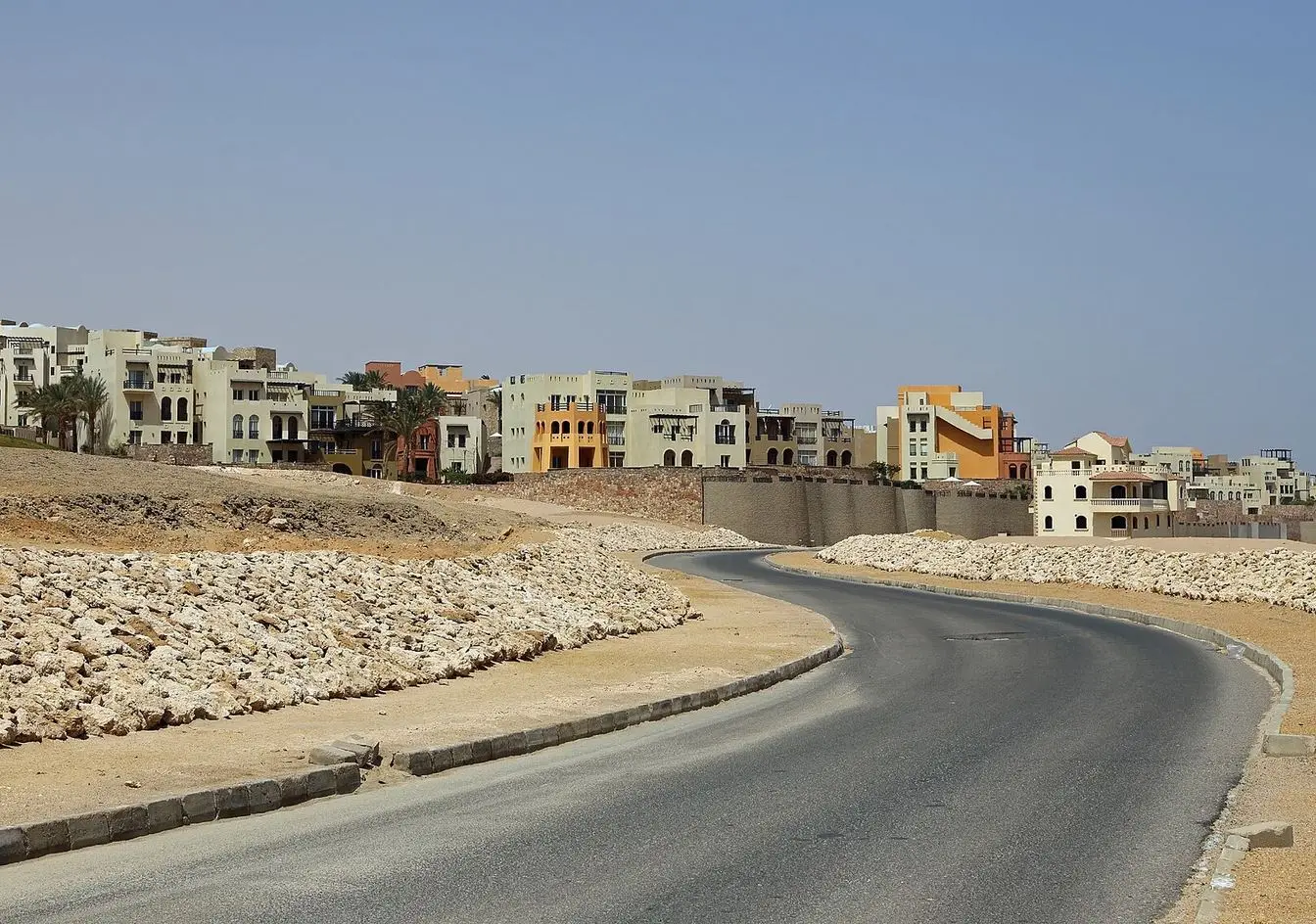 A road curving through Sahl Hasheesh, with completed resort buildings on one side and bare, undeveloped rocky ground on the other. File photograph of the area, not a picture of the 375-feddan plot named in the letter.